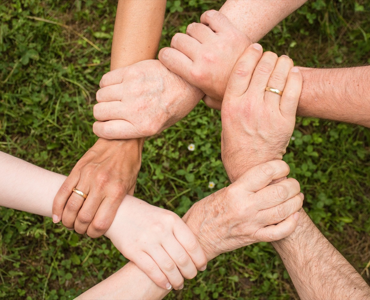 Four people gripping each other's wrists to form a linked square.