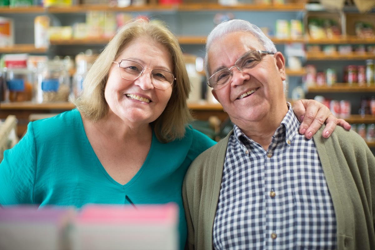 An older couple smiling together while out at a local shop.