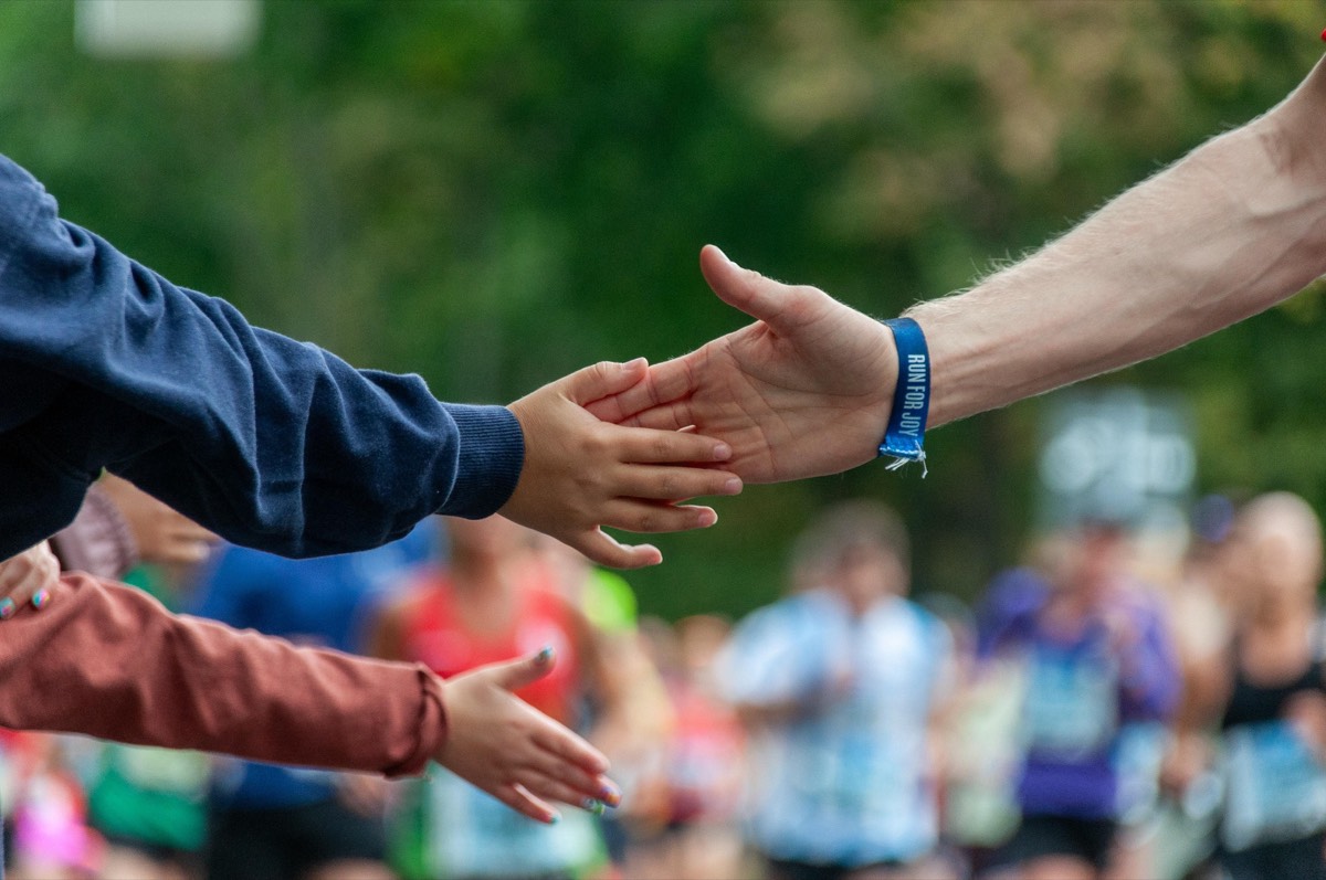 Two people reaching out to take one another's hand.
